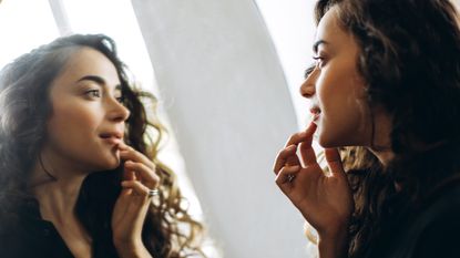 woman checking her skin in bathroom mirror