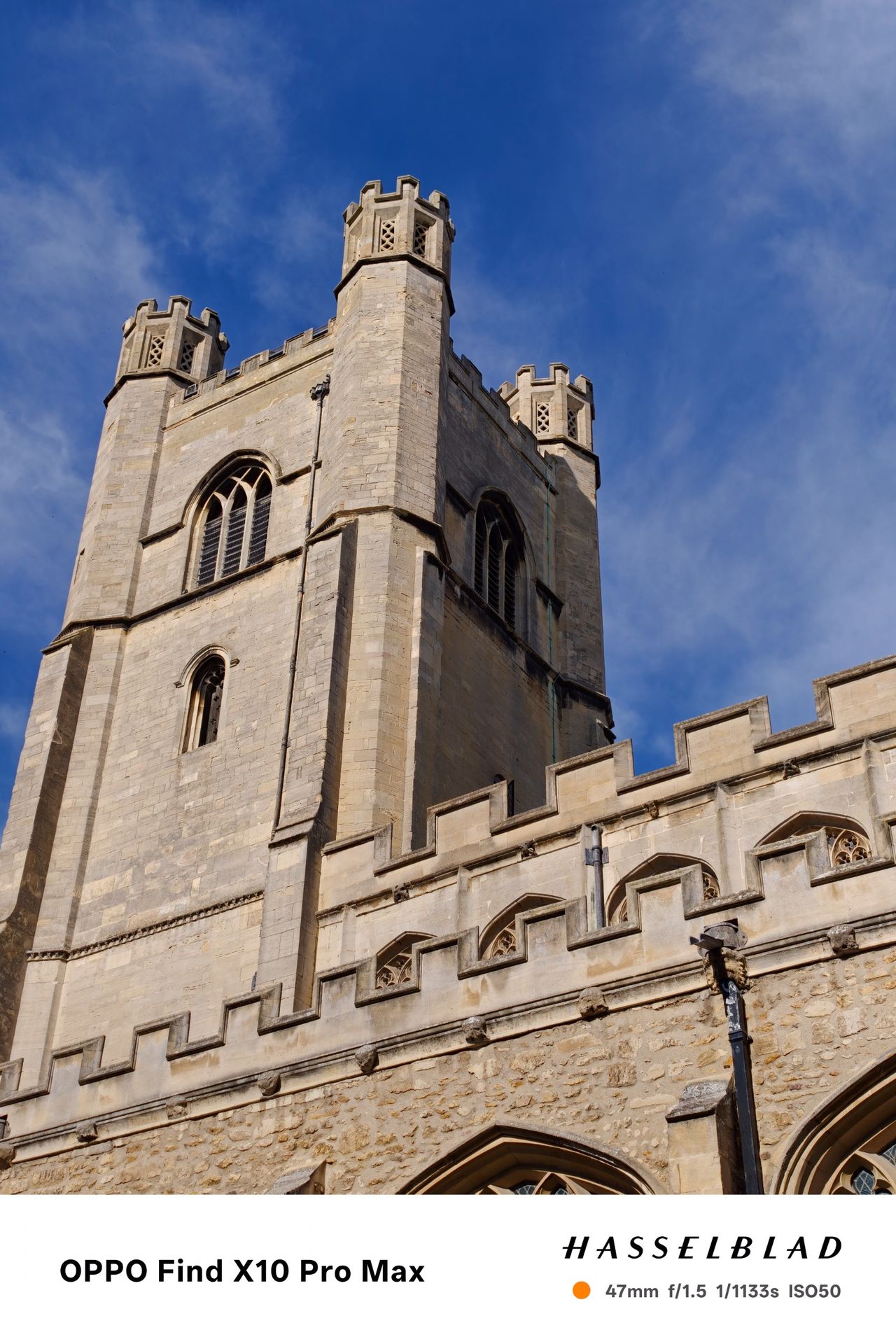 Stone church tower photographed from below against a deep blue sky.