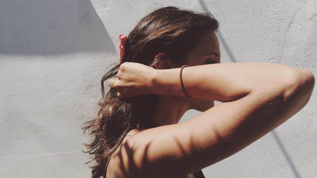 Side View Of Woman Tying Hair Into Ponytail - stock photo