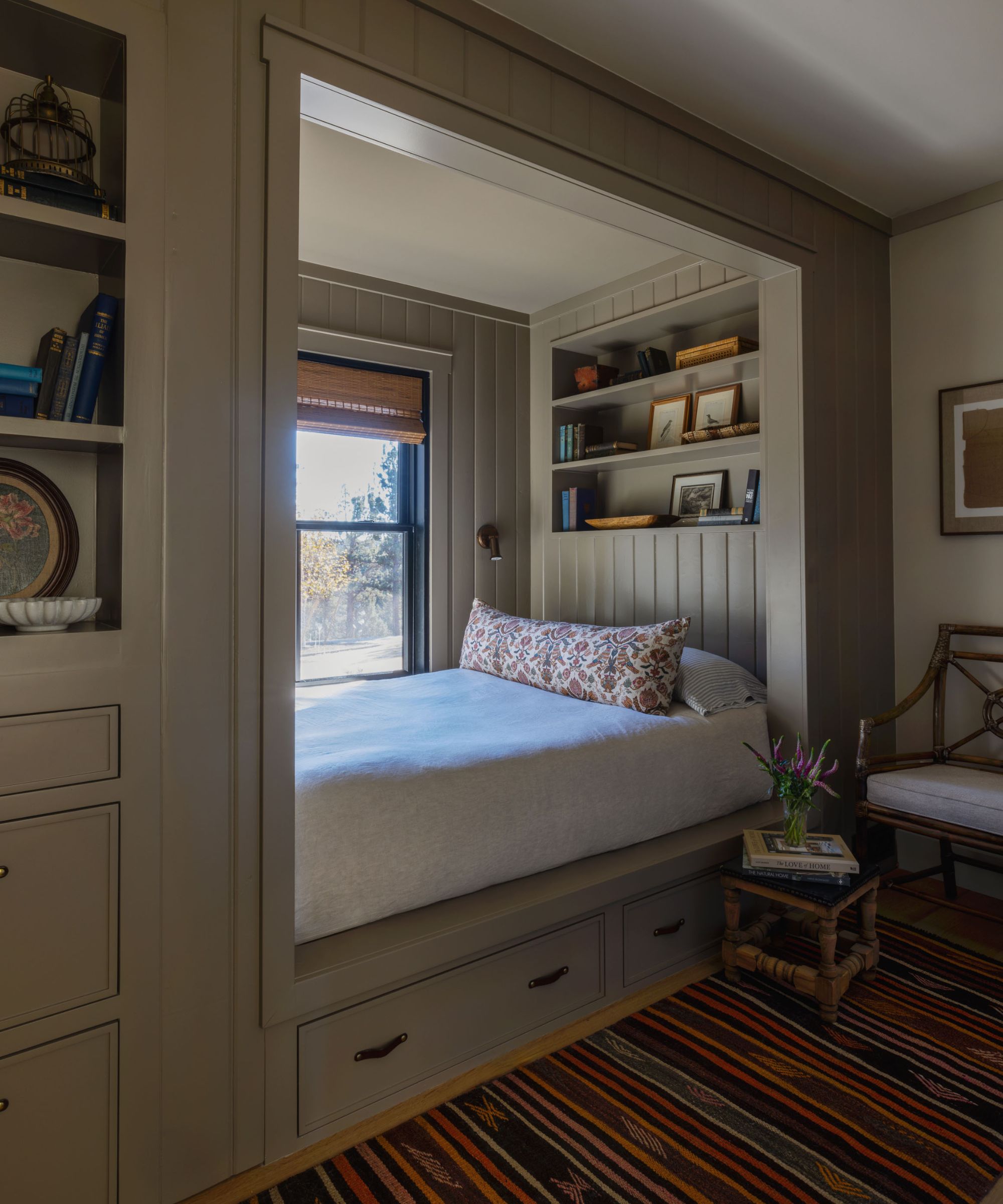 Built-in bed with shelving, drawers below, and a striped rug on the floor
