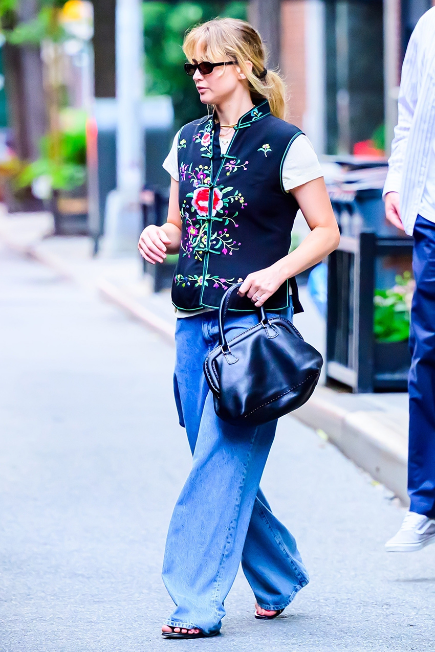 Jennifer lawrence wearing a navy vintage vest, white T-shirt, baggy jeans, and vintage Fendi Selleria doctor bag
