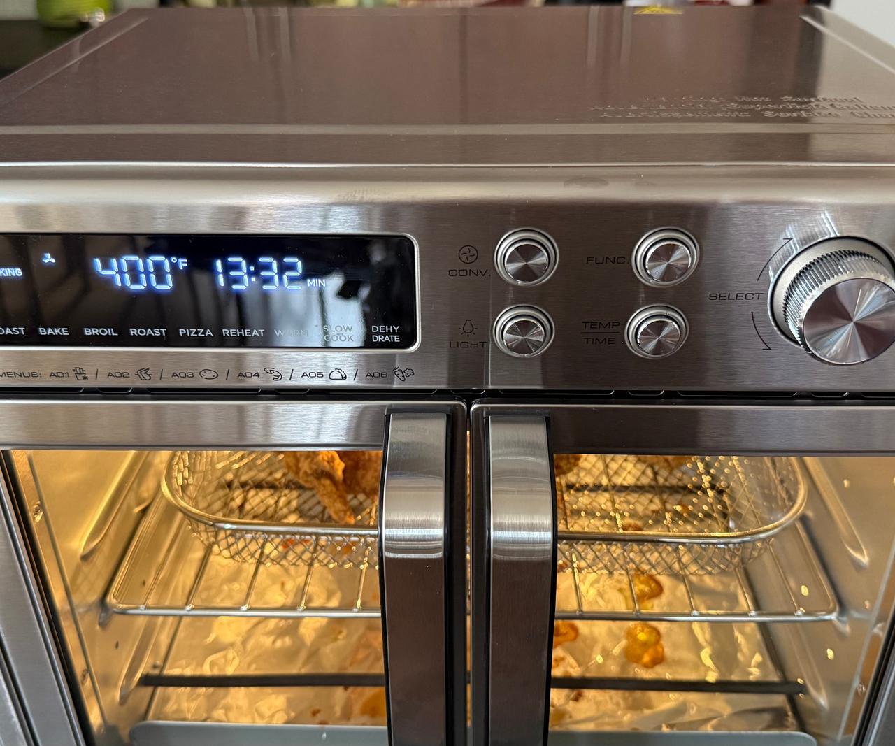 A close up of the digital display on the front of a stainless steel two door air fryer oven with blue numbers.