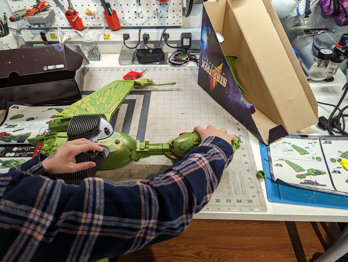 a child assembles a klingon bird of prey on a workbench