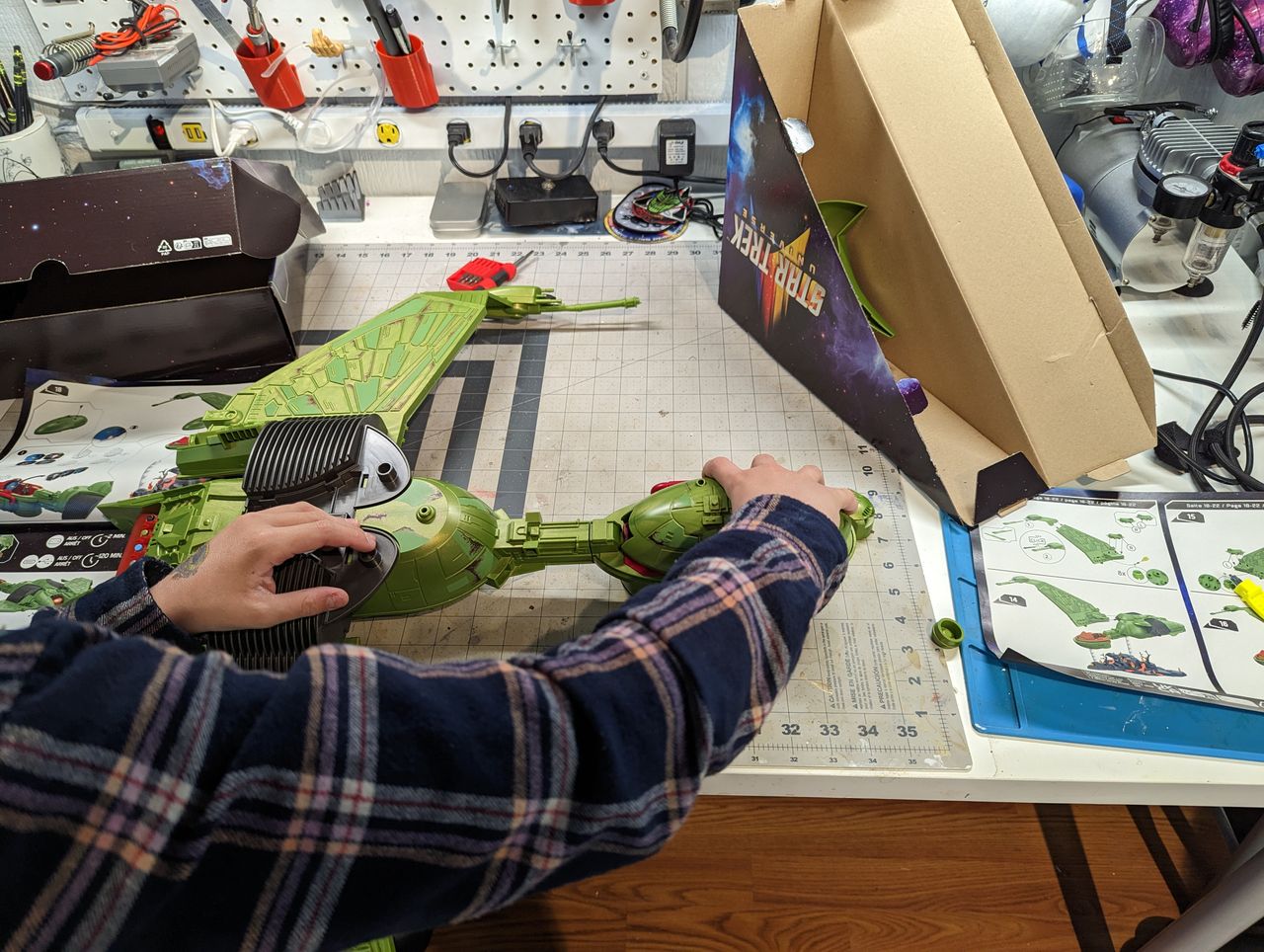 a child assembles a klingon bird of prey on a workbench