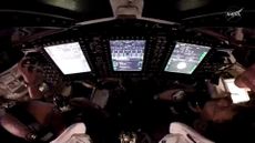 A look into a dark cockpit with three bright white computer screens
