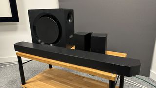 Samsung HW-Q990D soundbar system slight angle with all components on wooden TV bench