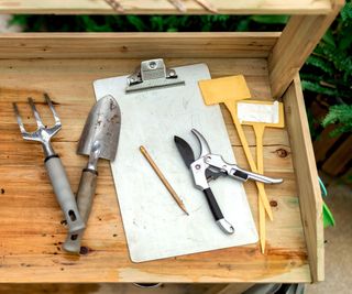 Pruners, a pencil, garden tools, and plant labels on a potting table