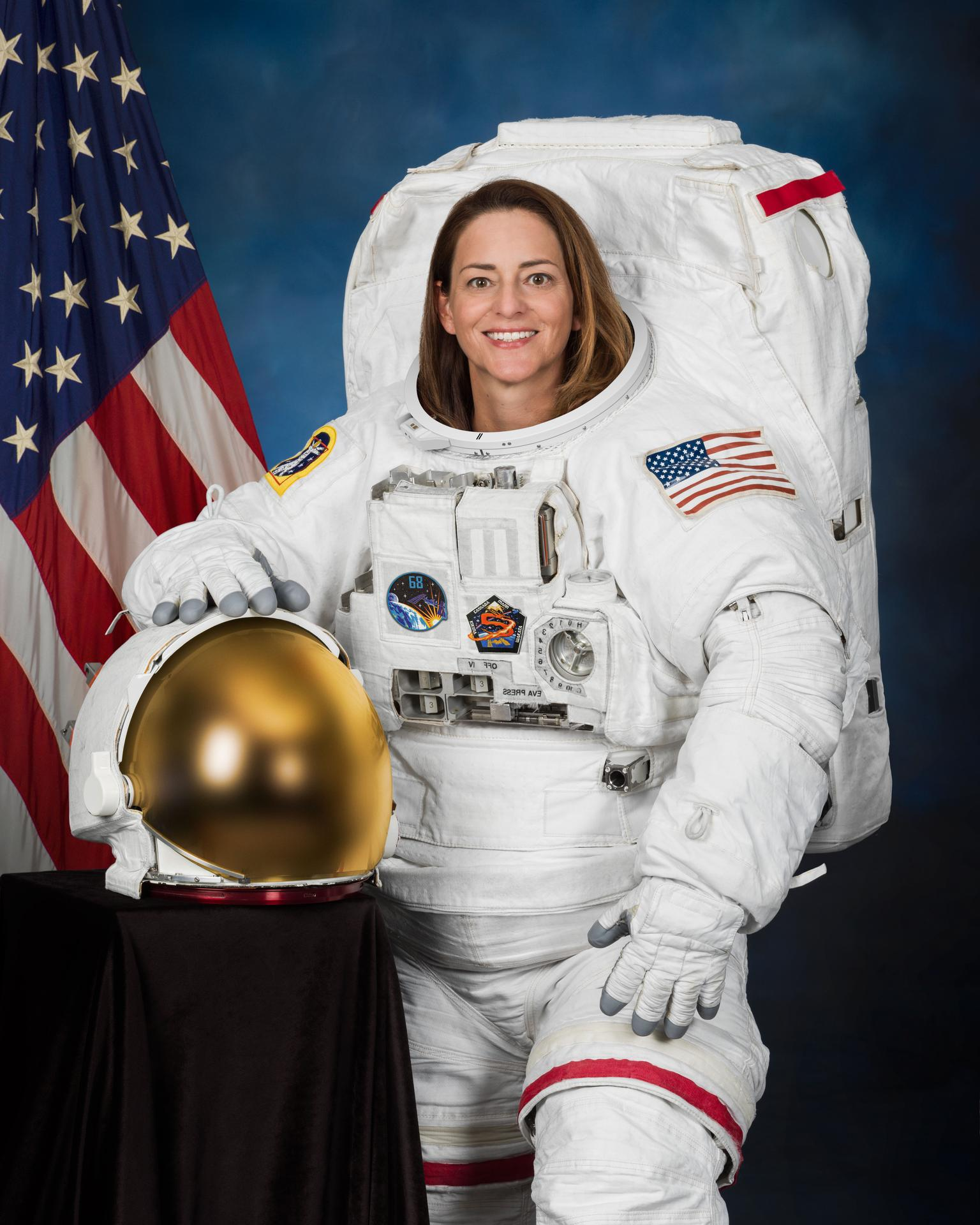 A woman smiles in a big white spacesuit.