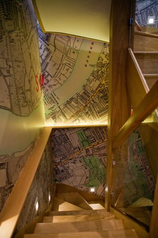 View looking down lit staircase with map artwork on walls