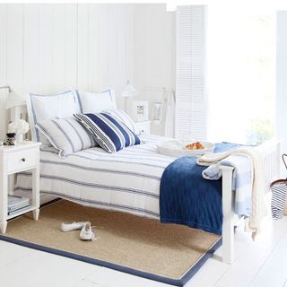 summer bedroom with nautical theme wooden shutters and sisal bed