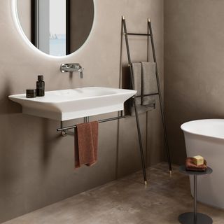 wabi sabi style bathroom with textured floor tiles, modern sink, ladder towel, white bath, modern side table, LED round mirror