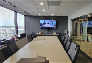 A meeting room with a display for a videoconference powered by ClearOne audio solutions.