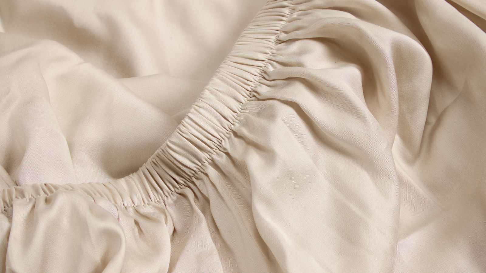 A close up shot of a cream fitted sheet that's part of the Coop Tencel range