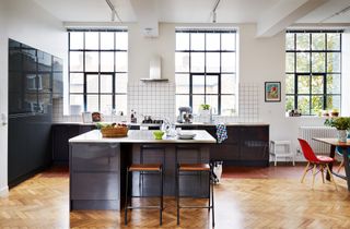 industrial-style kitchen with dark blue units, parquet flooring and grid-pattern white backsplash tiles