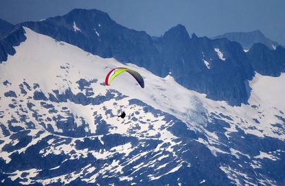 A paraglider soars along an Alaskan mountain range.