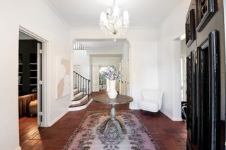 A modern entryway with white walls, terracotta tiles and Persian rug
