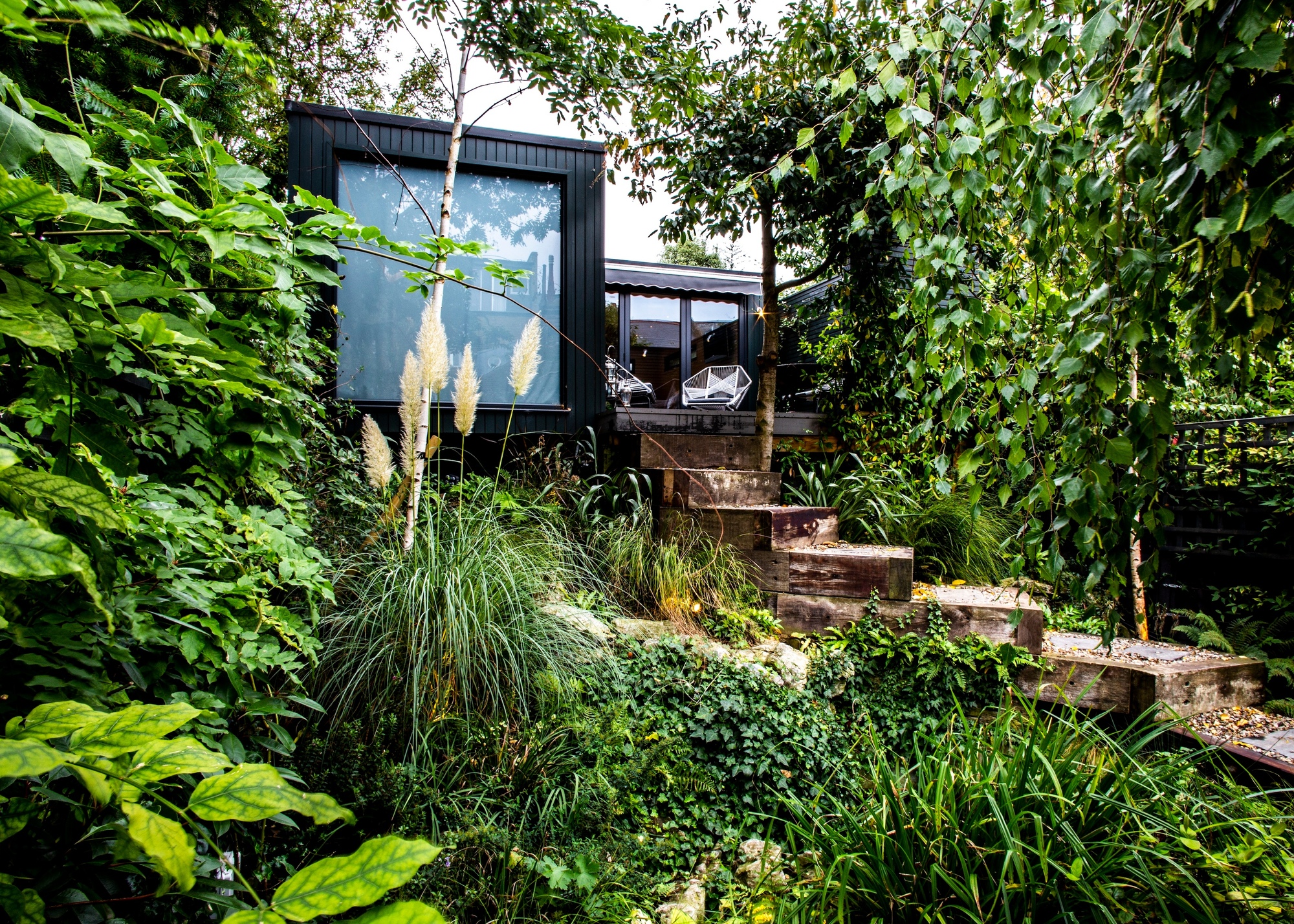 Garden room at the top of some steps surrounded by trees and plants