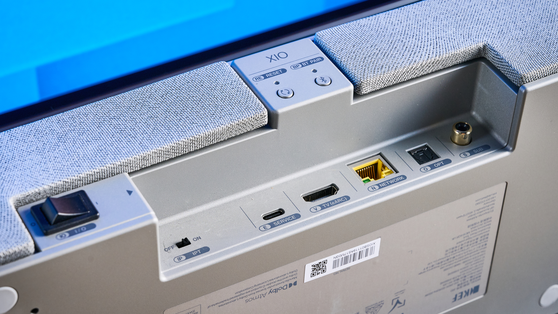 the KEF XIO soundbar in gray photographed with a TV and the Tom's Guide blue background