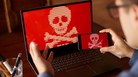 A man receiving a ransomware attack on both his phone and laptop - a poor day for the stock image actor.
