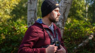 A man in a forest in a red coat wearing a GoPro Chesty V2 harness with GoPro Hero 12 Pro attached