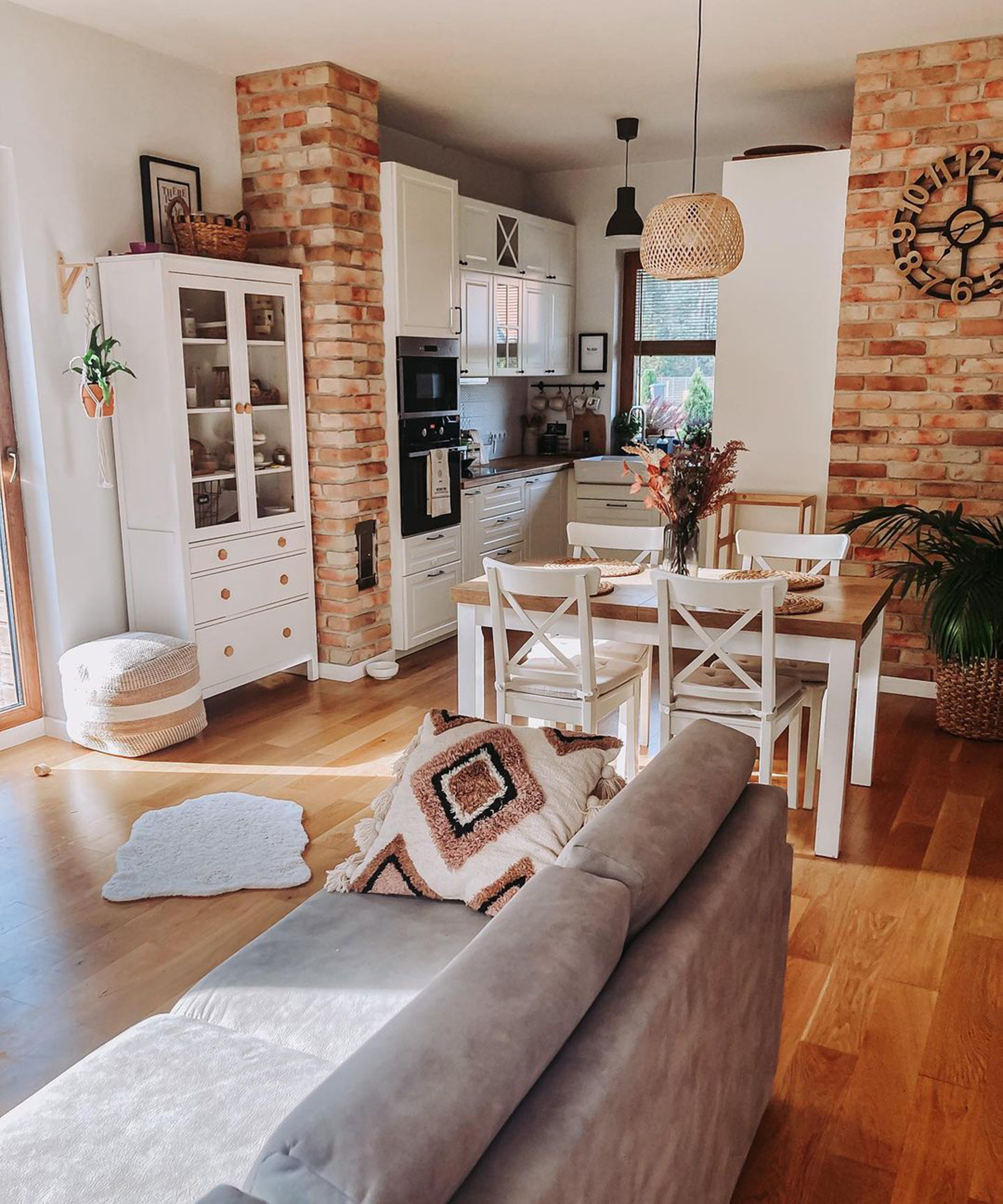 A dining idea for small kitchens with exposed brick wall, white dresser and white painted wooden dining set