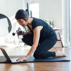 Simple home workouts: A woman loading a workout on her laptop at home
