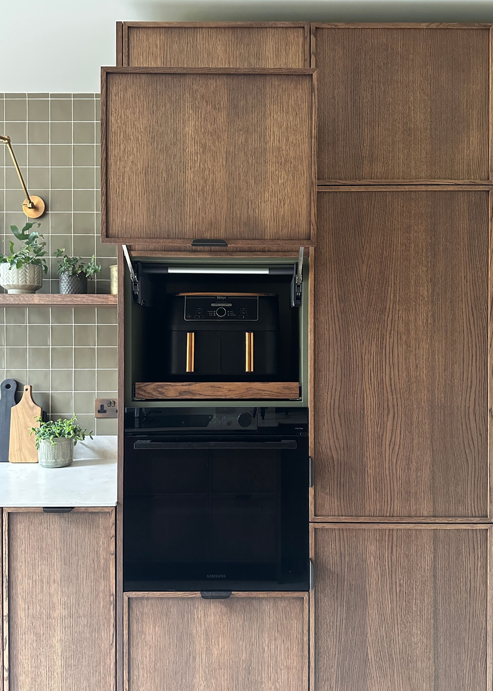 A kitchen with a hidden storage solution and space for an airfryer. The airfryer sits above the oven, next to the kitchen counters