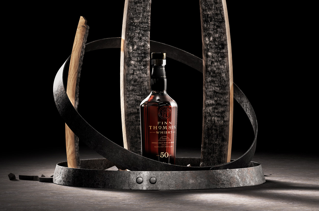 A bottle of whisky standing between staves of wood against a black background