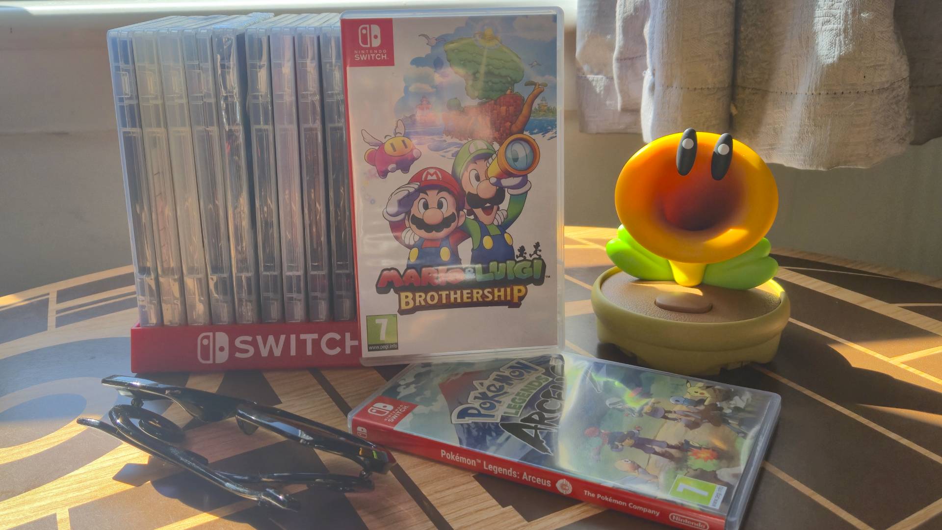 Photo of a pile of Switch games sitting on a sun-lit coffee table.