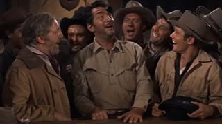Dean Martin shares a laugh with a crowd at the saloon in The Sons of Katie Elder.