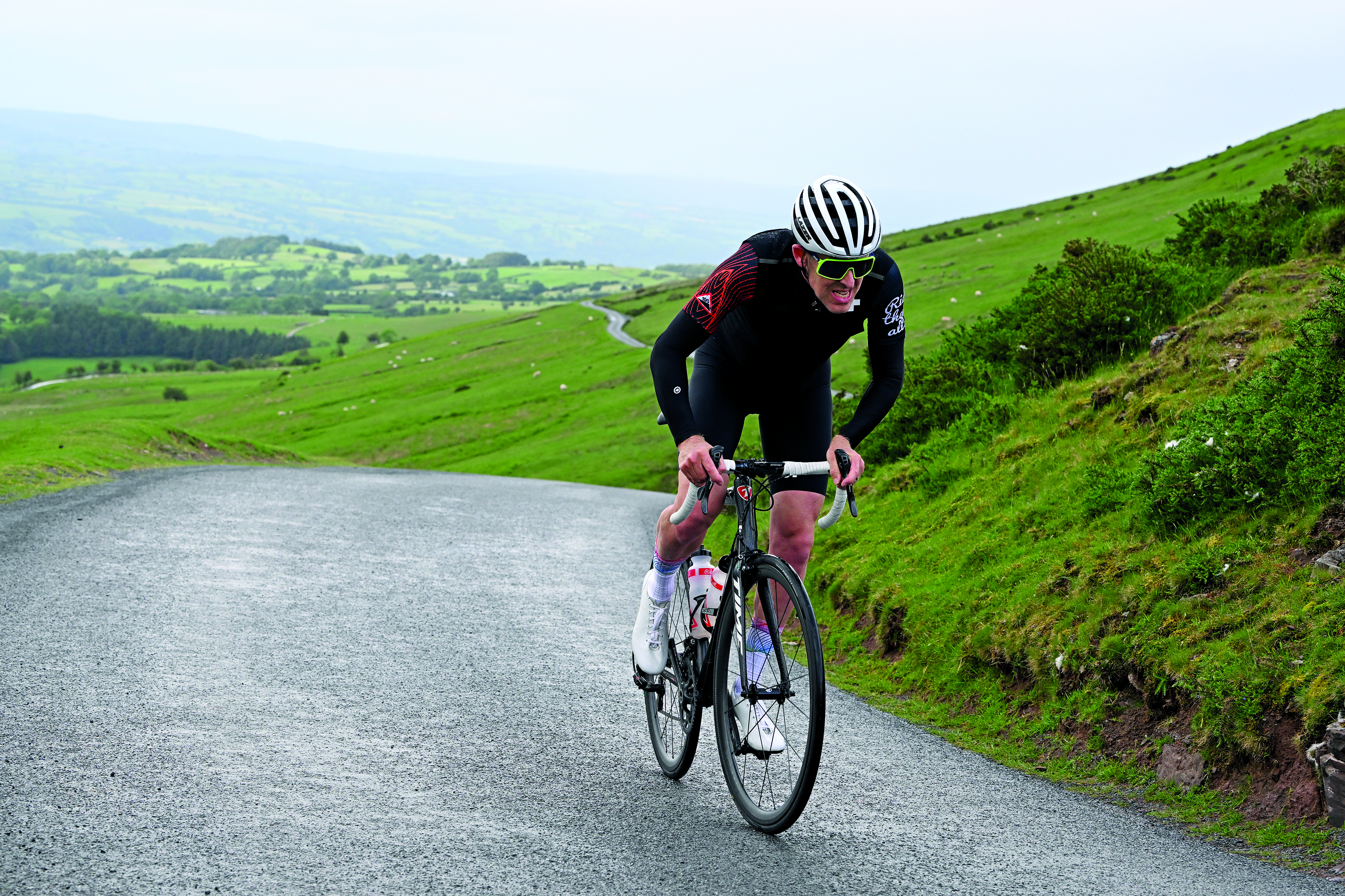 Simon Warren climbs on the hoods with a grimace on his face