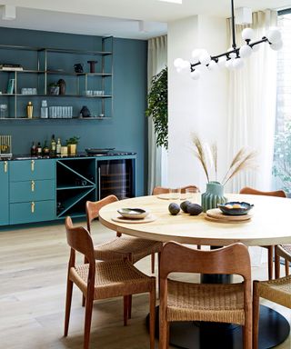 Dining area with blue walls and round wooden table in Victorian mews house in London with contemporary interior designed by Kitesgrove