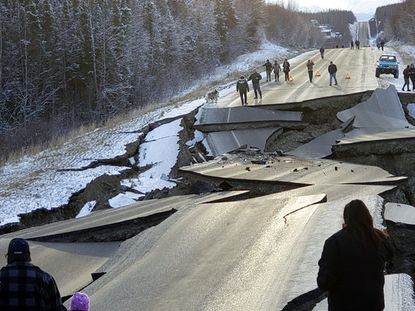 People walk along Vine Road after an earthquake, Friday, Nov. 30, 2018, in Wasilla, Alaska. 