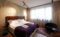 A bedroom in the Story Hotel with twin beds pushed together in the centre of an elegant room with gold wallpaper.