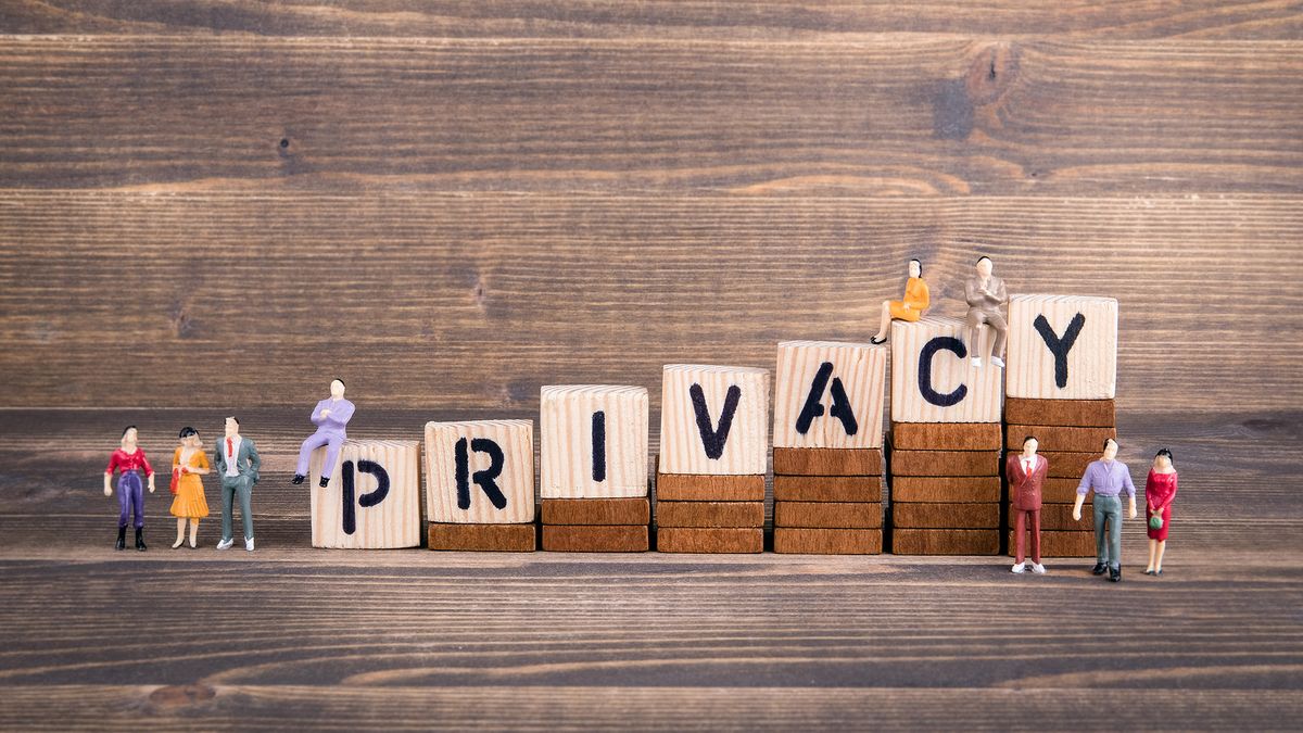 Some small models of people sitting on wooden blocks that spell out the word privacy