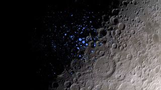 a section of the surface of the moon, half shaded and dark from the top left corner. illuminated blue splotches litter the middle of the image, denoting dark craters that never get light.