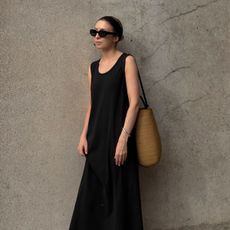 Woman wears black sunglasses, black dress and basket bag