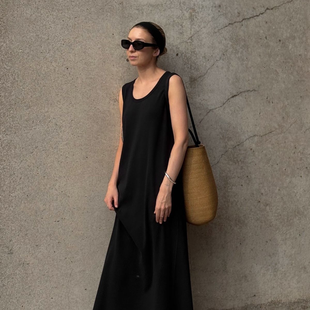 Woman wears black sunglasses, black dress and basket bag