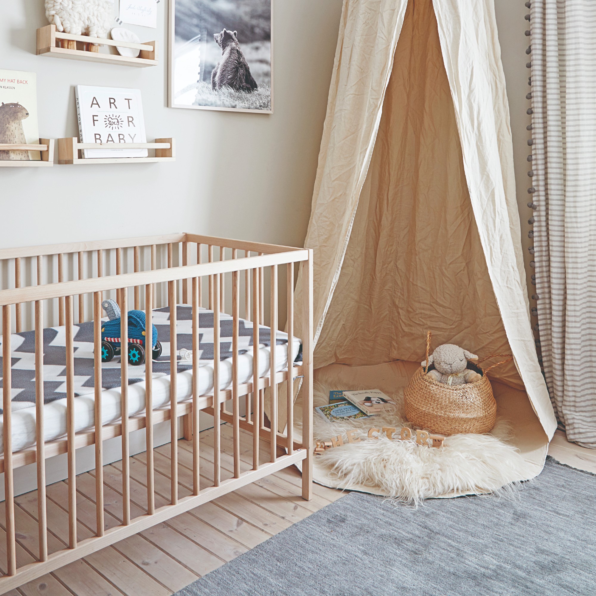 A Scandi-style nursery with wooden floors and a play nook with a canopy cover
