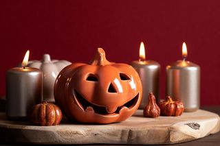 Autumn home decor with ceramic pumpkins and lit candles.