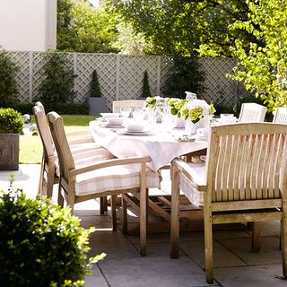 traditional summer garden with green trees and wooden table with chairs
