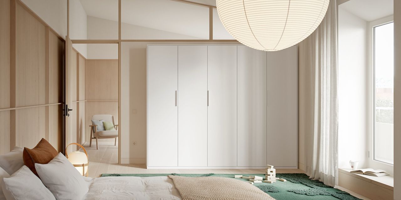 A bedroom showing a large white built-in closet and paper lampshade