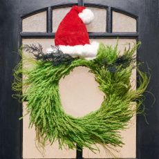 grinch christmas wreath with pampas grass topped with an assortment of bright neon painted leaves and black asparagus