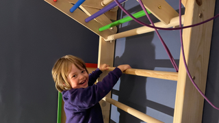 Image of a toddler climbing up a wall climber at home