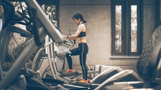 Woman in a gym checking how to use an elliptical machine with correct form