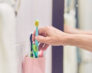 Person taking toothbrush out of a toothbrush holder