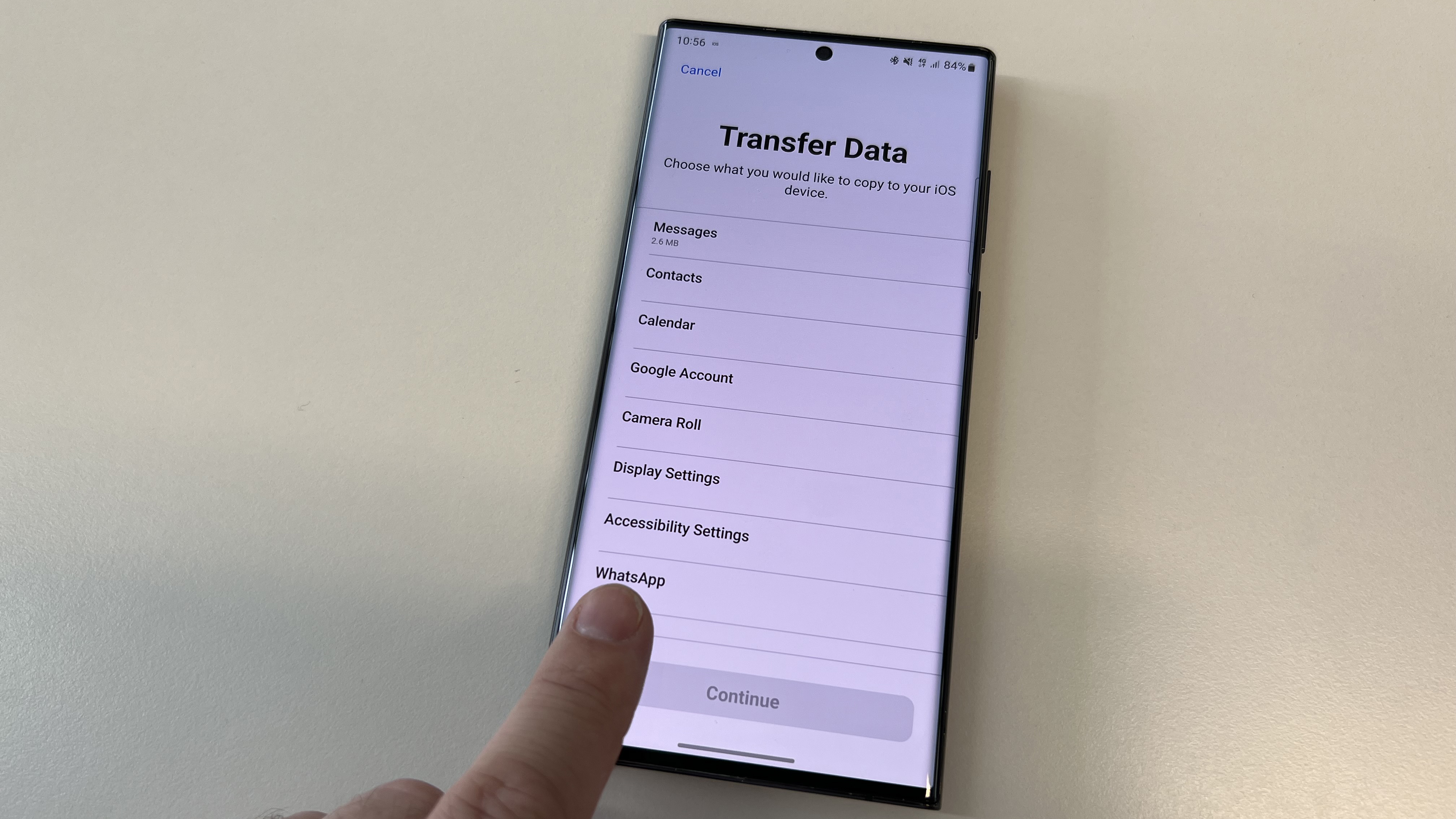 The data transfer screen of the Move to iOS app, with a finger pointing at the WhatsApp section
