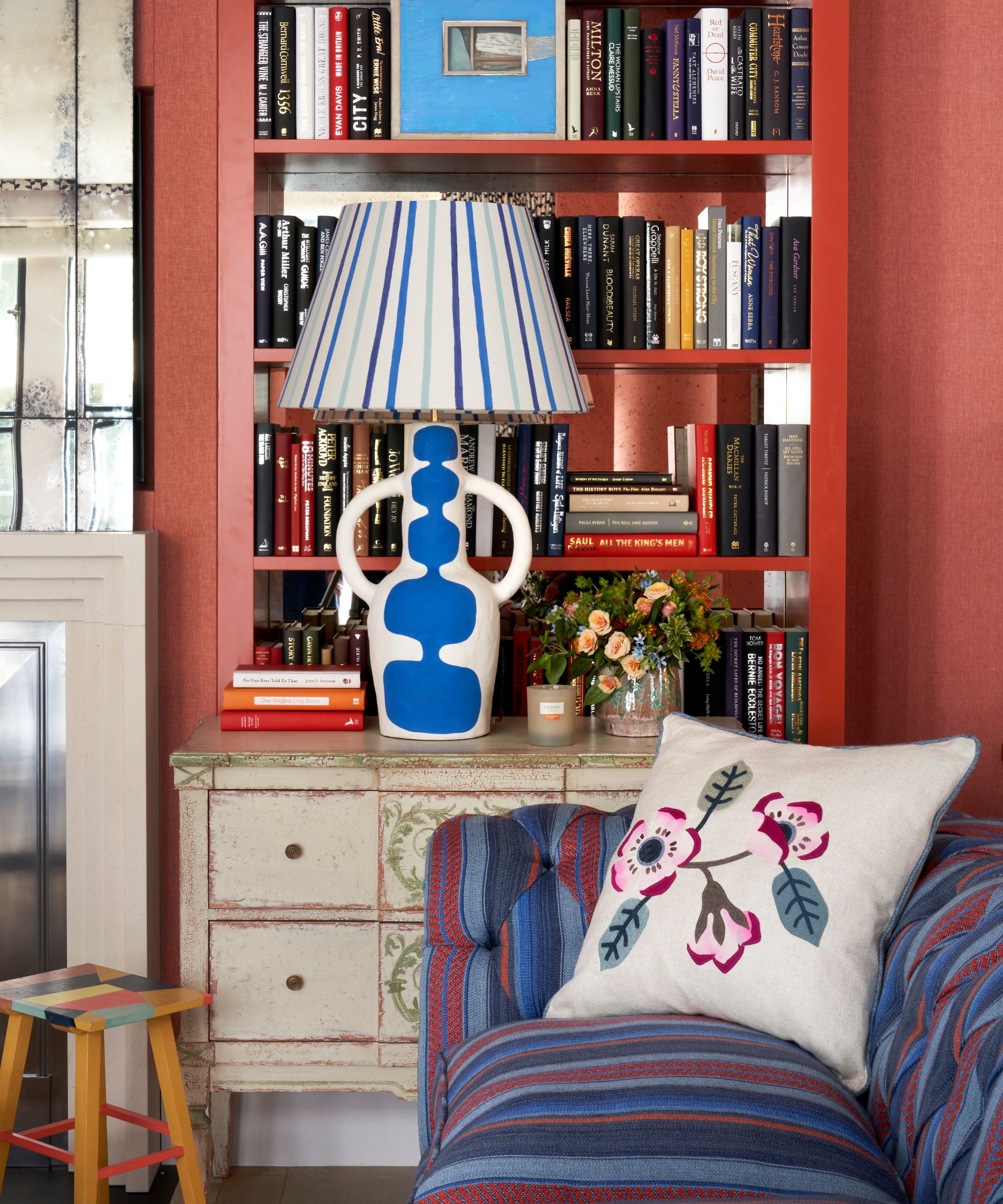 red living room alcove with built in bookcase styled with a blue and white striped lamp