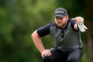 Jordan Smith crouches down behind a putt at the 2024 BMW International Open