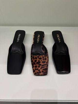 Three pairs of square-toe Prada kitten heel mules, two in black and one leopard print.